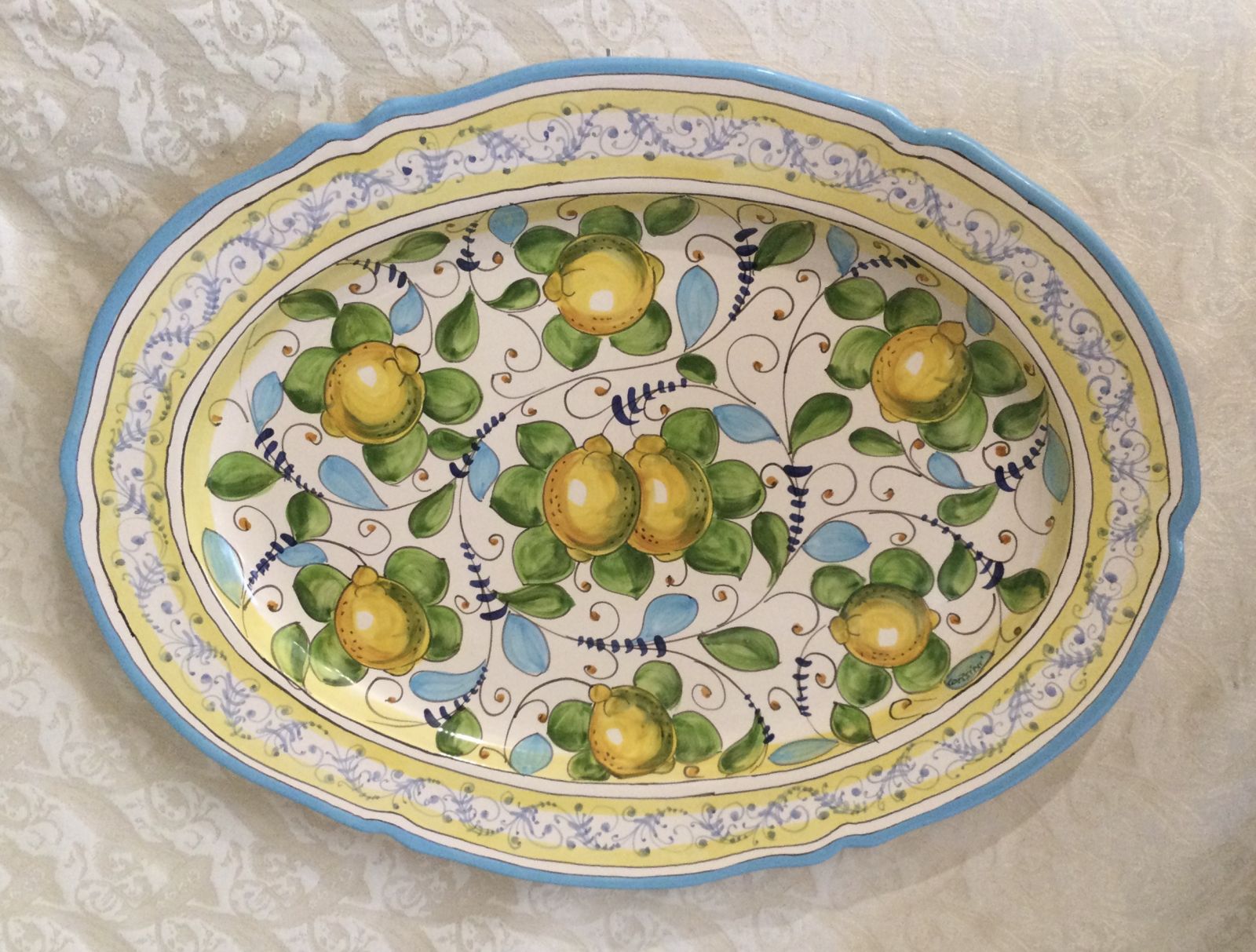 Oval scalloped plate 56x43 cm lemons with green and light blue leaves and light blue crown